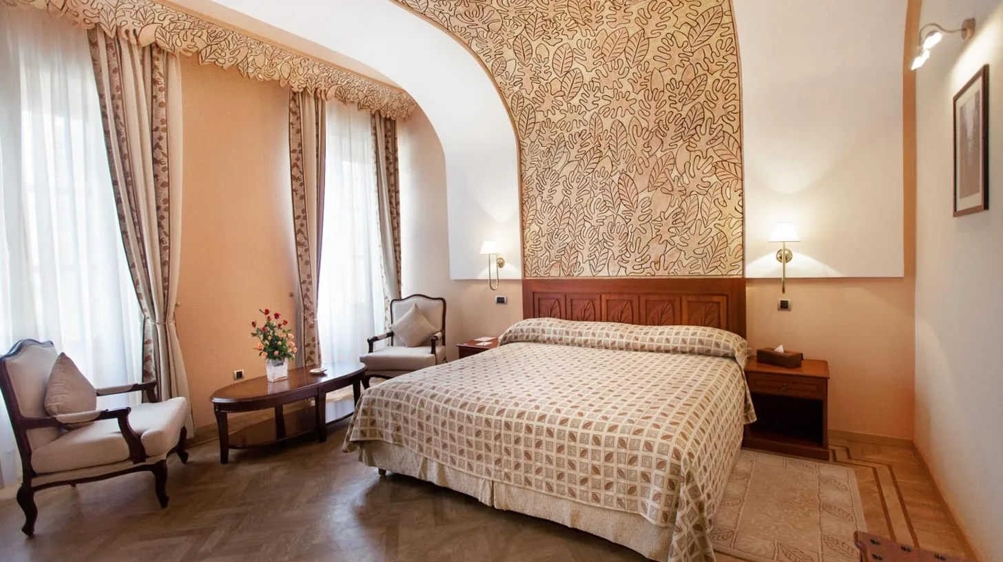 a bedroom with a bed and a chair at Grand Hotel Villa de France in Tangier