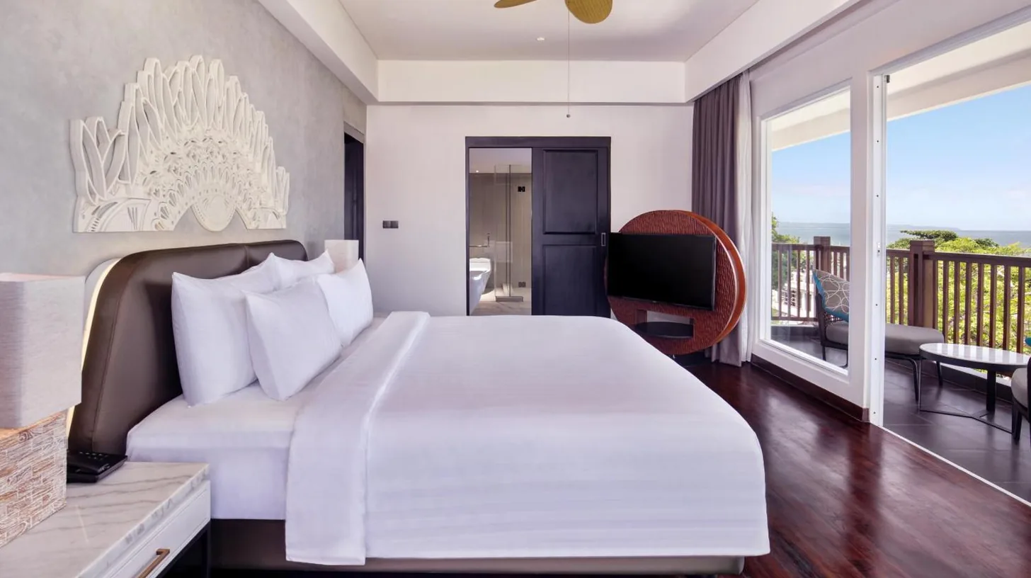 a bedroom with a large bed and a living room at Grand Mercure Bali Seminyak in Seminyak
