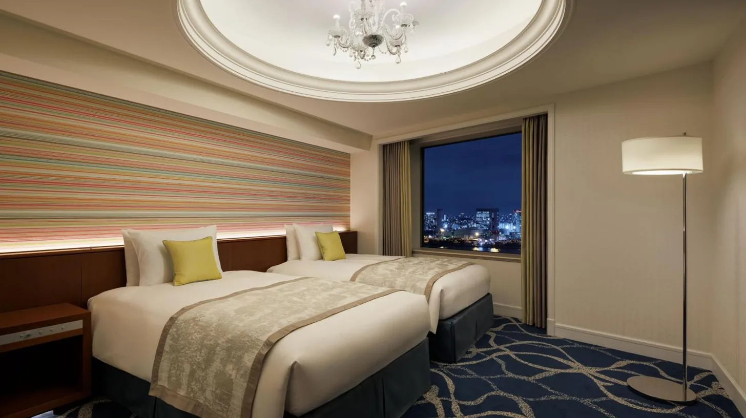 two beds in a hotel room with a window at Grand Nikko Tokyo Daiba in Tokyo