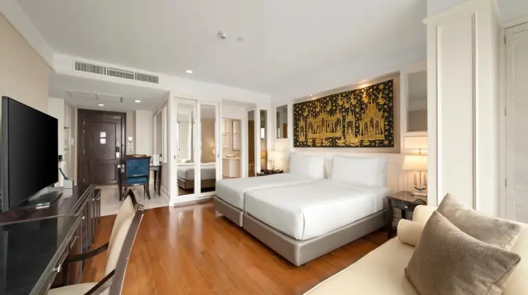 a bedroom with a bed and a living room at Grande Centre Point Hotel Ratchadamri Bangkok in Bangkok