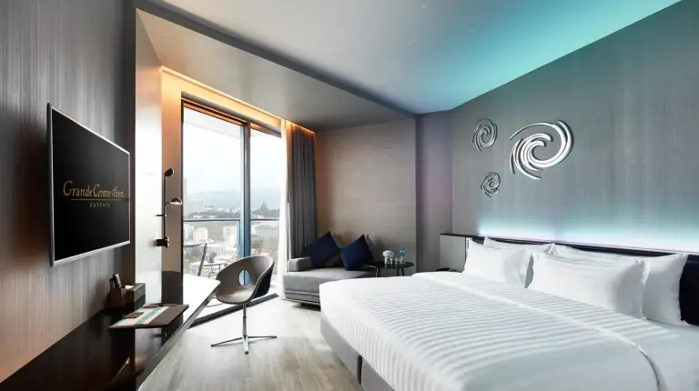 a hotel room with a large bed and a couch at Grande Centre Point Pattaya in Pattaya Central
