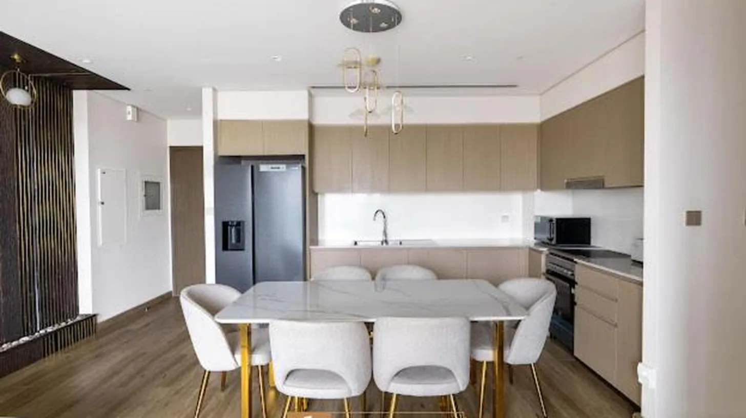 a kitchen with a white table and white chairs at Grande Signature Residences in Dubai