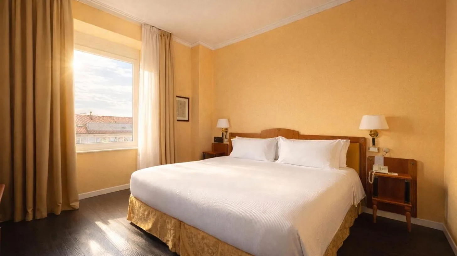 a bedroom with a large white bed and a window at Greif Hotel & Spa in Trieste
