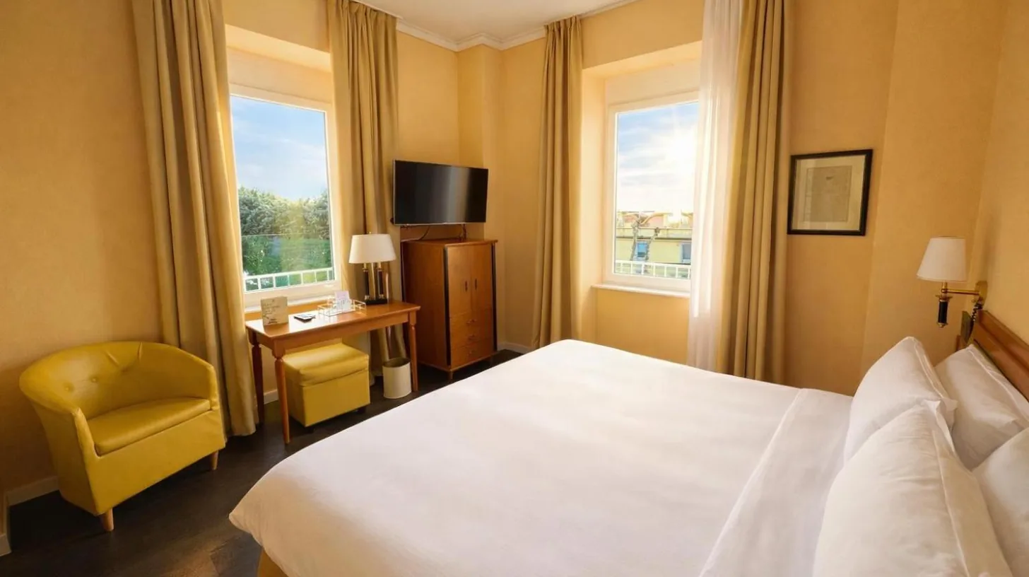 a hotel room with a bed and a desk and window at Greif Hotel & Spa in Trieste