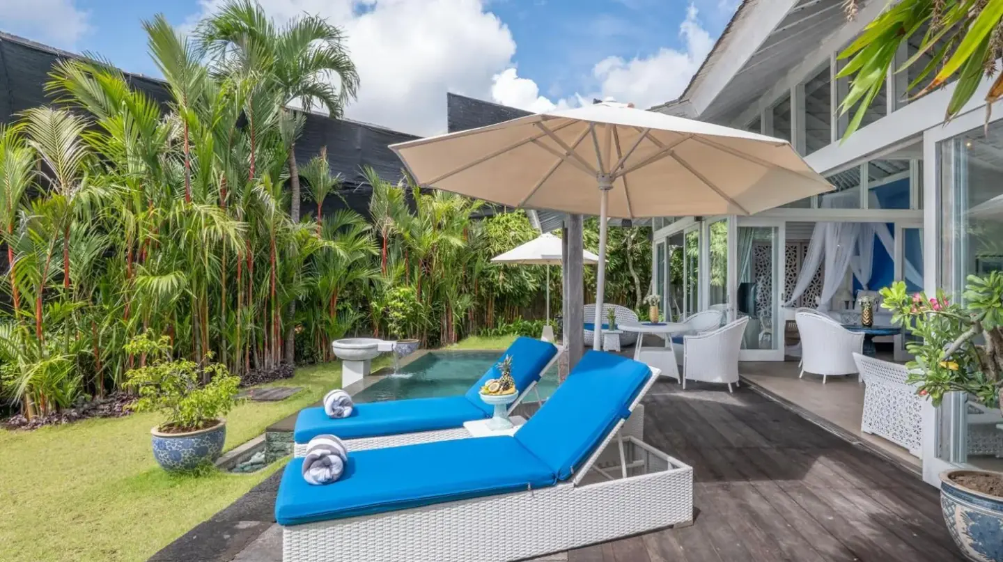 a patio with two blue chairs and an umbrella at Hidden Hills Villas - Small Luxury Hotels of The World in Uluwatu