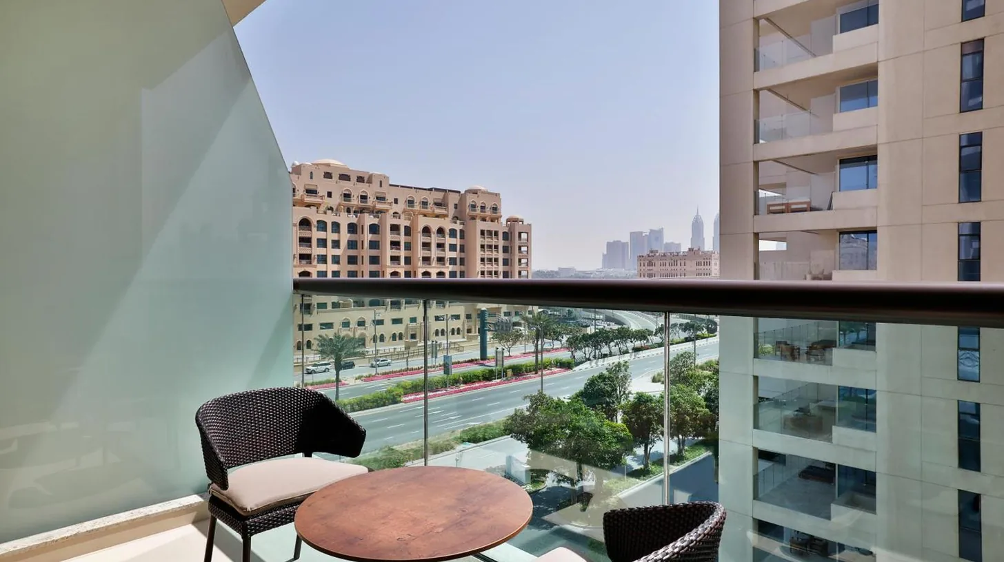 a balcony with chairs and a table and a view of a city at Hilton Dubai Palm Jumeirah in Dubai