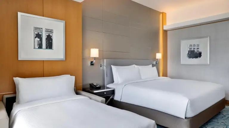 two beds in a hotel room with white sheets at Hilton Dubai Palm Jumeirah in Dubai