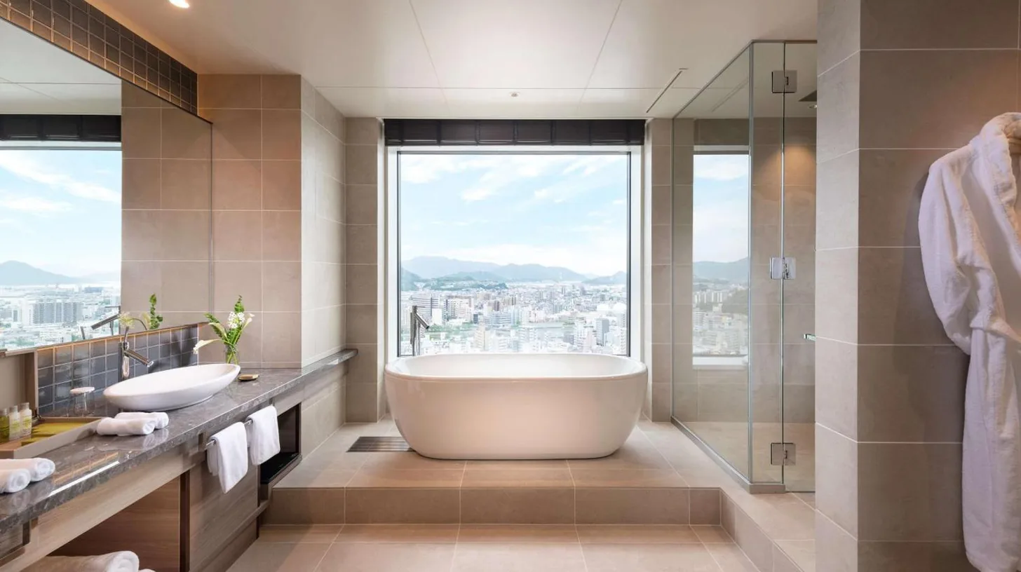 a bathroom with two sinks and a tub and a window at Hilton Hiroshima in Hiroshima