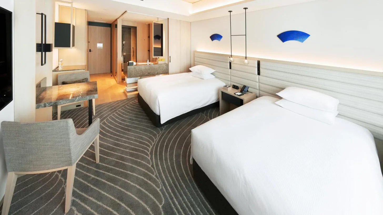 una habitación de hotel con dos camas y un escritorio en Hilton Nagasaki en Nagasaki