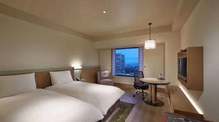 a hotel room with two beds and a desk and a window at Hilton Osaka Hotel in Osaka