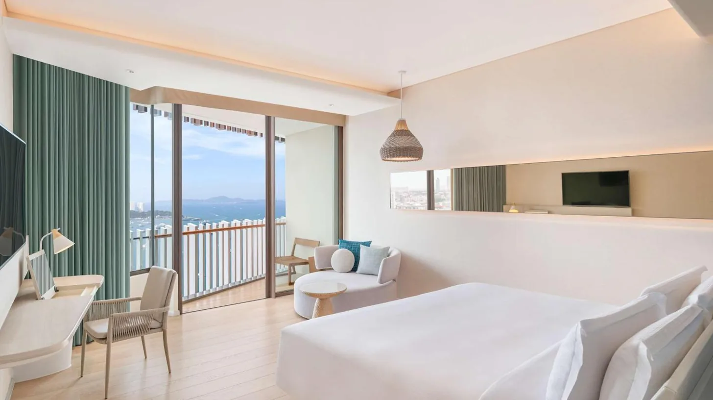 a hotel room with a large bed and a balcony at Hilton Pattaya in Pattaya Central