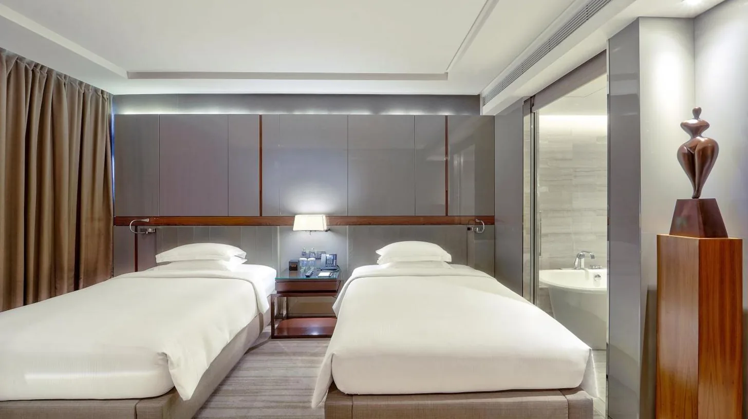 eine Frau sitzt im Bett und schaut auf ein Handy im Hilton Sukhumvit Bangkok in Bangkok