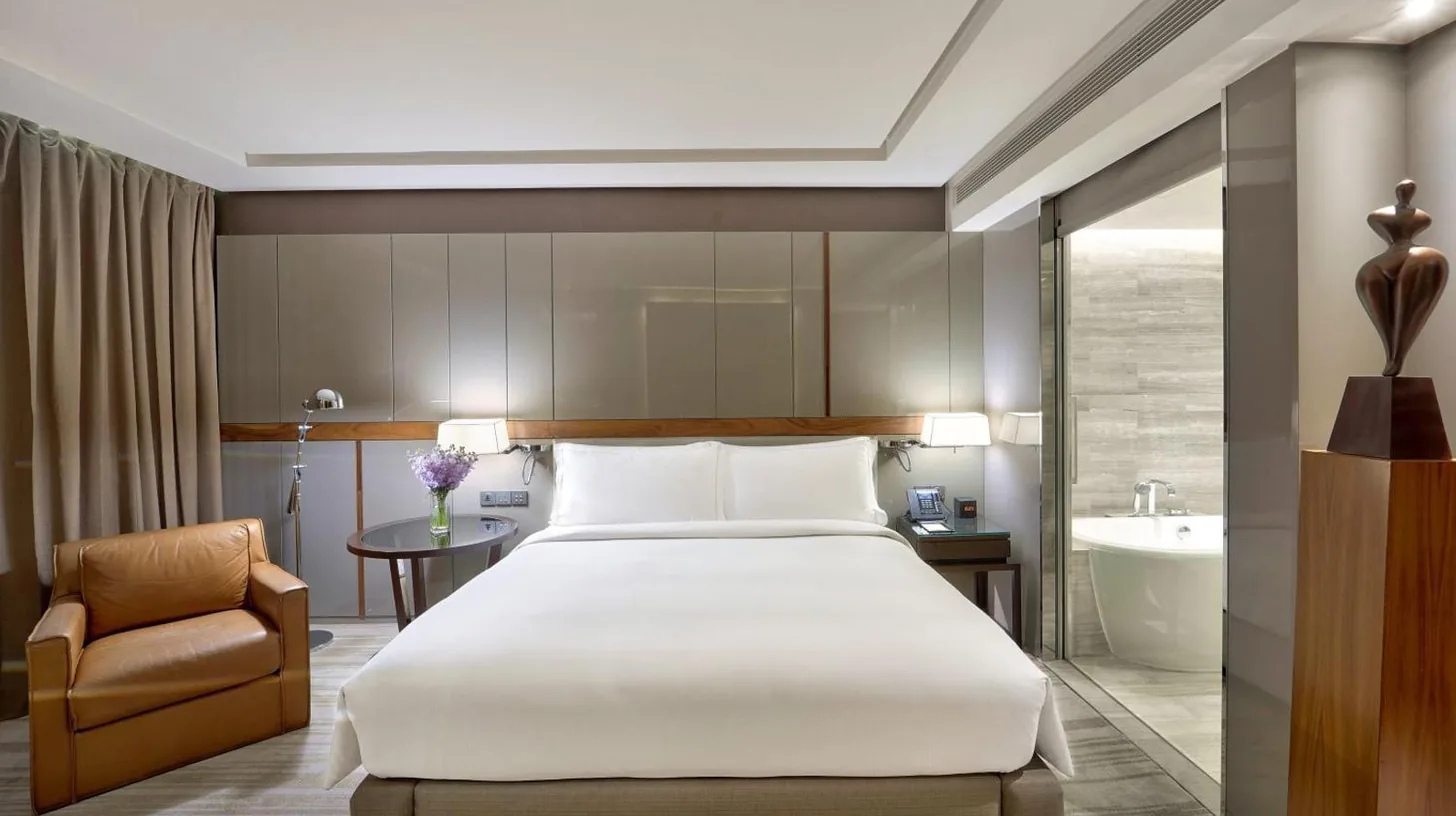 ein Restaurant mit Tischen, Stühlen und großen Fenstern im Hilton Sukhumvit Bangkok in Bangkok