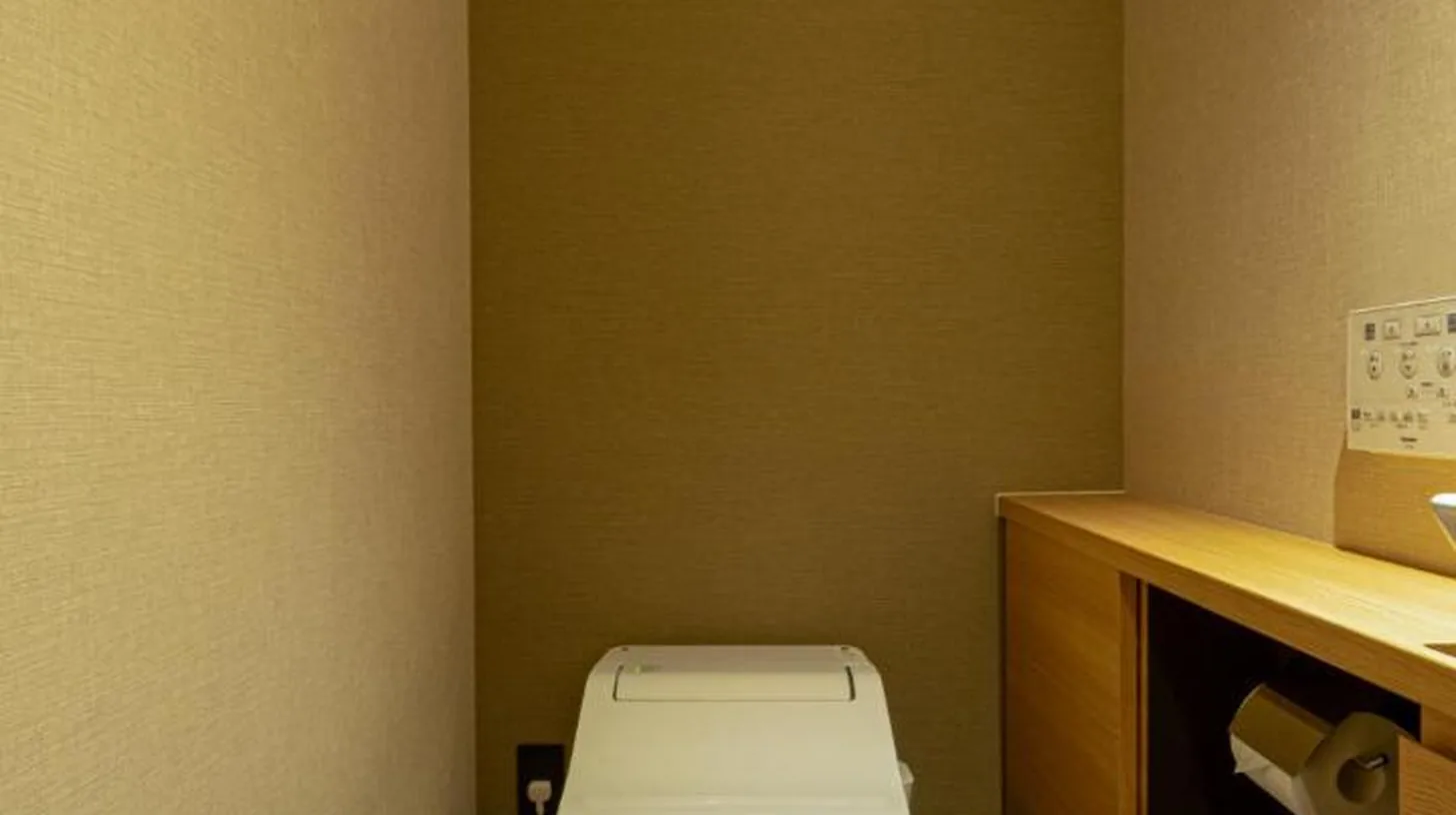 a bathroom with a toilet in the corner of a room at Homm Stay Nagi Shijo Kyoto By Banyan Group in Kyoto