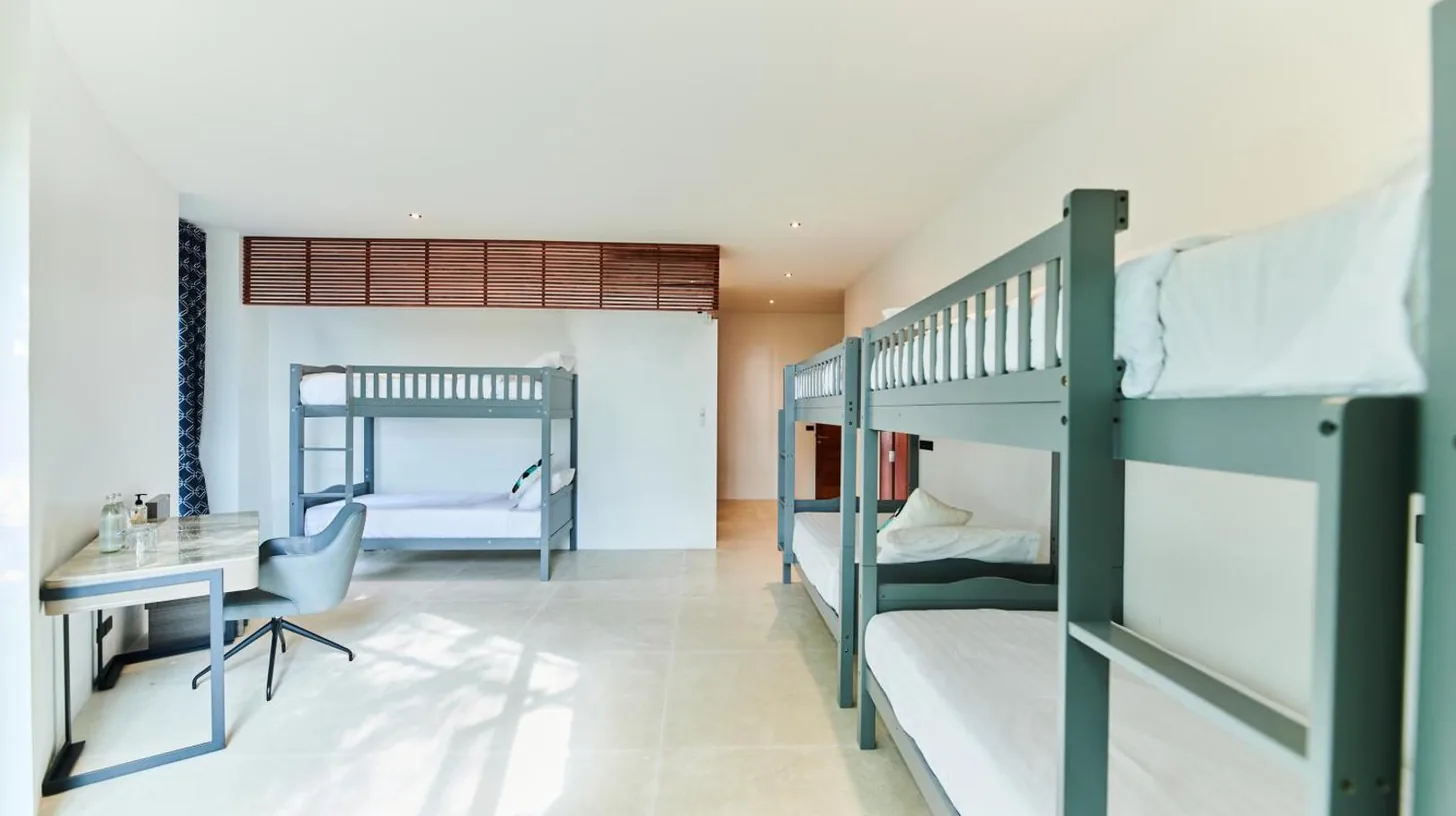 zwei Etagenbetten in einem Zimmer mit Tisch und Schreibtisch bei naked Home Baan Jakawan Koh Samui in Chaweng