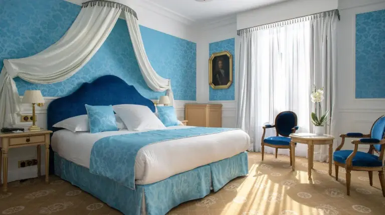 ein Schlafzimmer mit einem Bett und einem Raum mit blauen WÃ¤nden im Hotel Le Negresco in Nizza