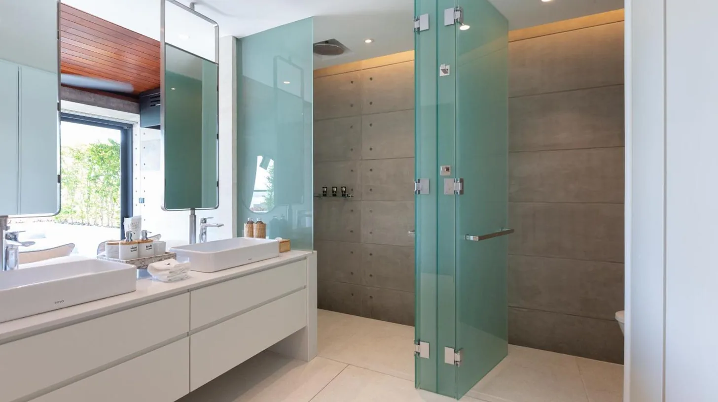 a bathroom with two sinks and a glass shower at Kerem Luxury Beachfront Villas in Choeng Mon Beach