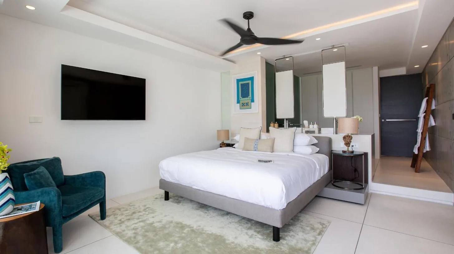 a bedroom with a bed and a tv and a chair at Kerem Luxury Beachfront Villas in Choeng Mon Beach