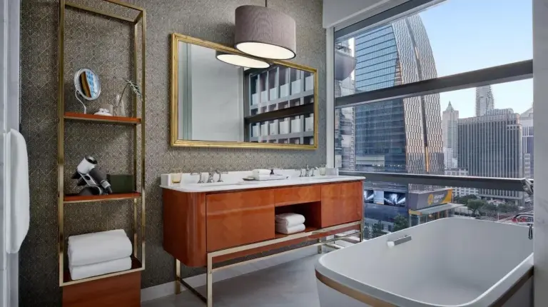 un baño con una bañera, un lavabo y una ventana en Rosewood Bangkok en Bangkok