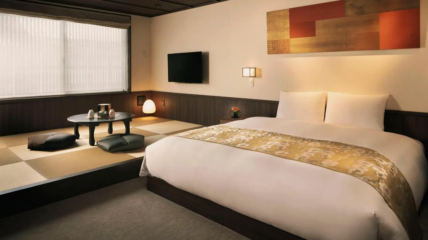 a hotel room with a large bed and a table at THE JUNEI HOTEL Kyoto Imperial Palace West in Kyoto
