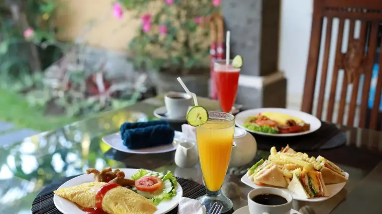 a table with plates of food and drinks on it at The Buah Bali Villas in Seminyak