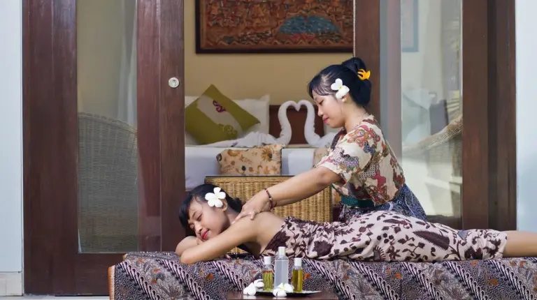 a woman cutting a girls hair on a bed at The Buah Bali Villas in Seminyak