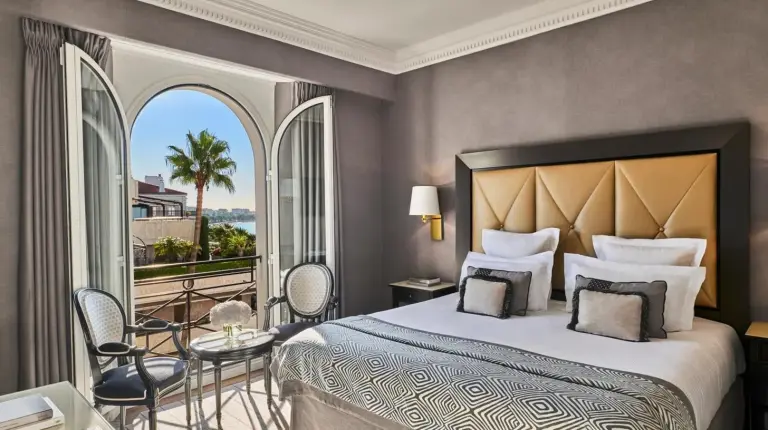 a bedroom with a large bed and a balcony at Hôtel Barrière Le Majestic Cannes in Cannes