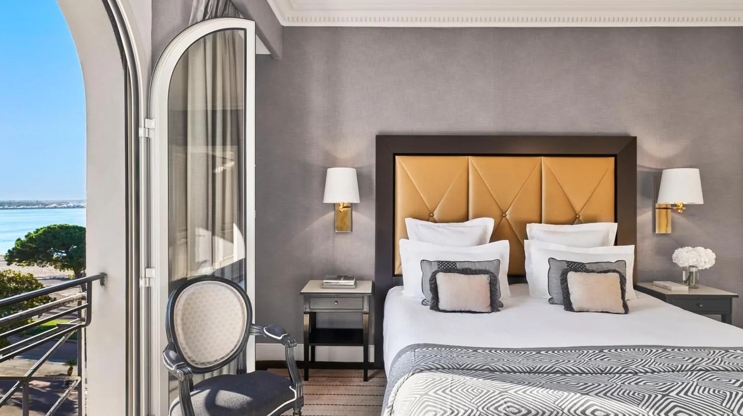 a hotel room with a bed and a balcony at Hôtel Barrière Le Majestic Cannes in Cannes