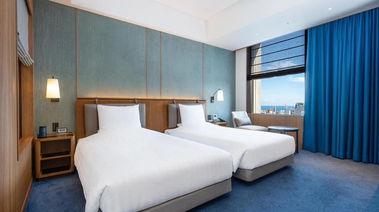 a hotel room with two beds and a window at Hotel Collective in Naha