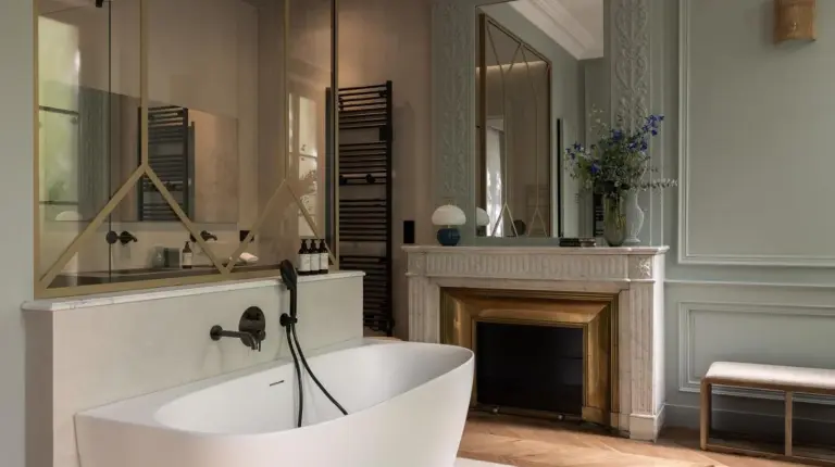 a bathroom with a white tub and a fireplace at Hotel des Quinconces Bordeaux Centre in Bordeaux