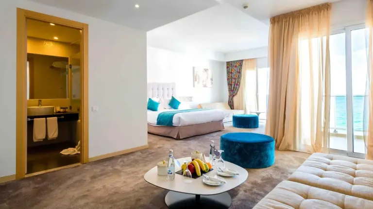 a hotel room with a bed and a living room at Hotel Farah Tanger in Tangier
