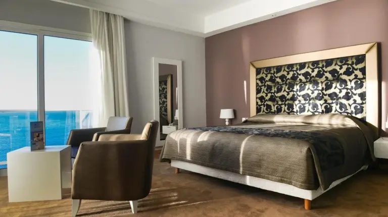 a bedroom with a large bed and a chair at Hotel Farah Tanger in Tangier