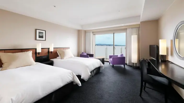 a hotel room with two beds and a desk at Hotel Granvia Kyoto in Kyoto