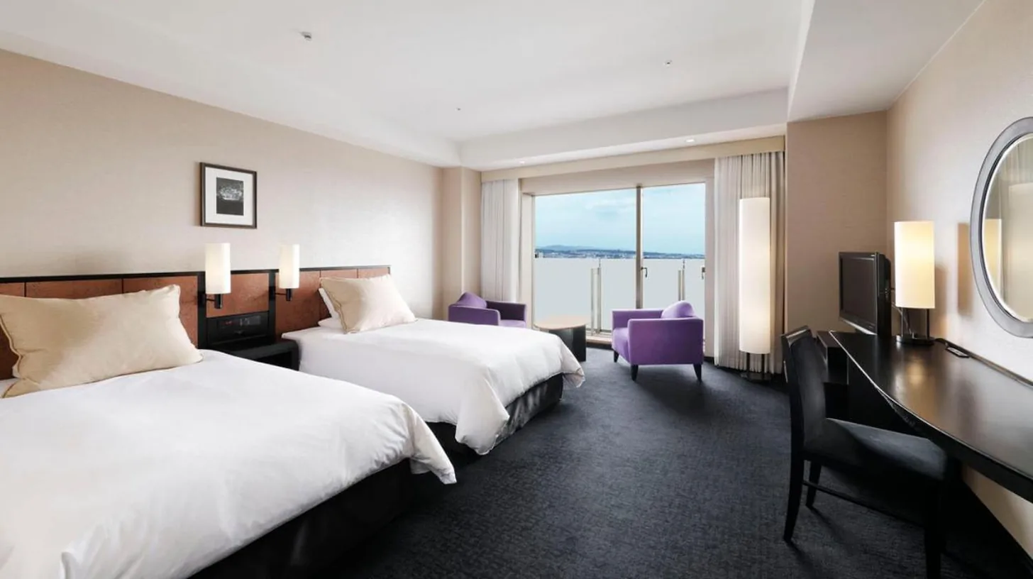 a hotel room with two beds and a desk at Hotel Granvia Kyoto in Kyoto