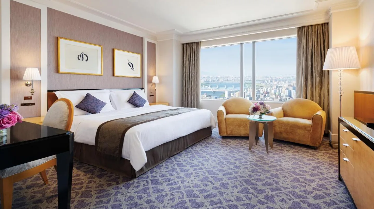 a living room with a bed and a large window at Hotel Hankyu International in Osaka