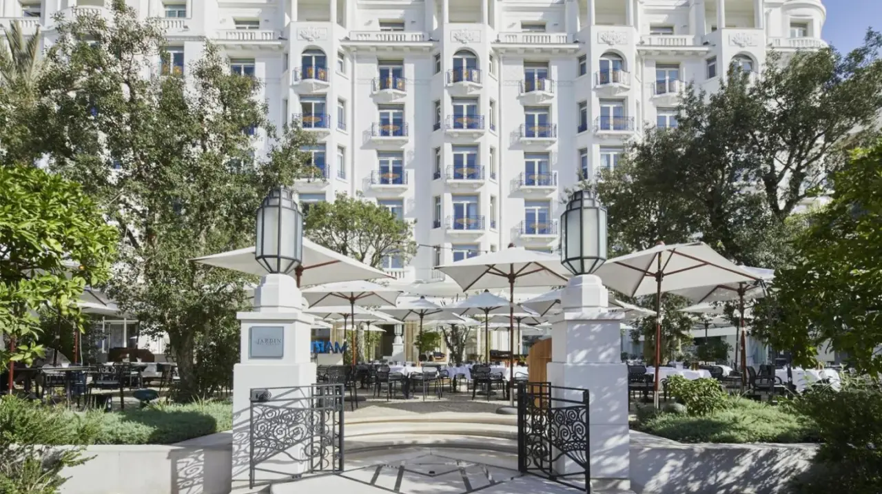 a hotel with tables and umbrellas in front of a building at HÃ´tel Martinez