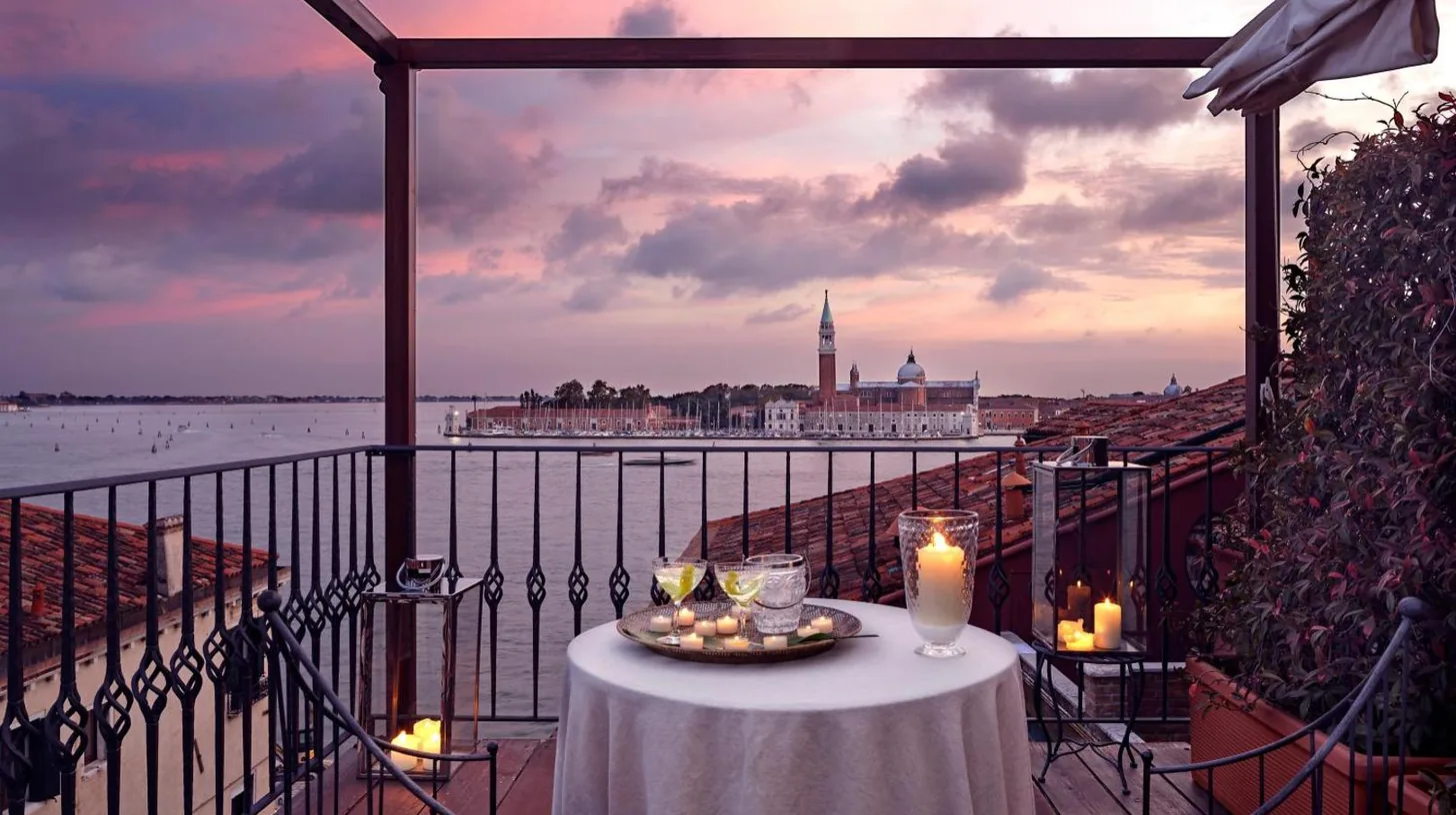 a table on a balcony with a view of the water at Hotel Metropole Venezia in Venice