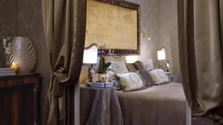 a bed with pillows and a table with a lamp at Hotel Metropole Venezia in Venice