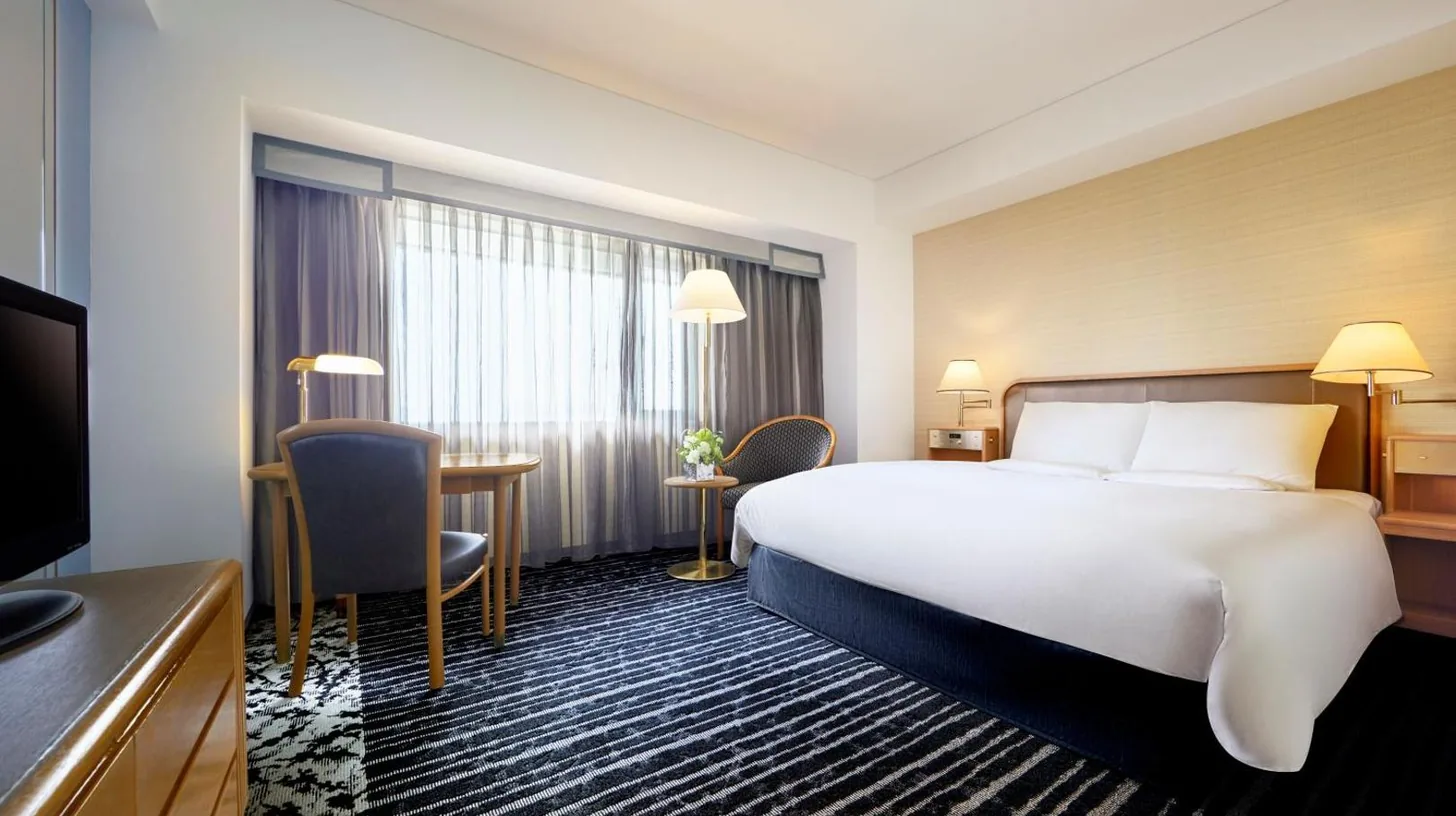 a hotel room with a large bed and a living room at Hotel New Otani Osaka in Osaka