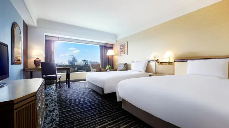 a hotel room with three beds and a large window at Hotel New Otani Osaka in Osaka