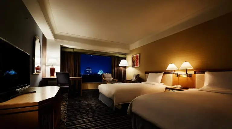 a bed with pillows with a view of a building at Hotel New Otani Osaka in Osaka