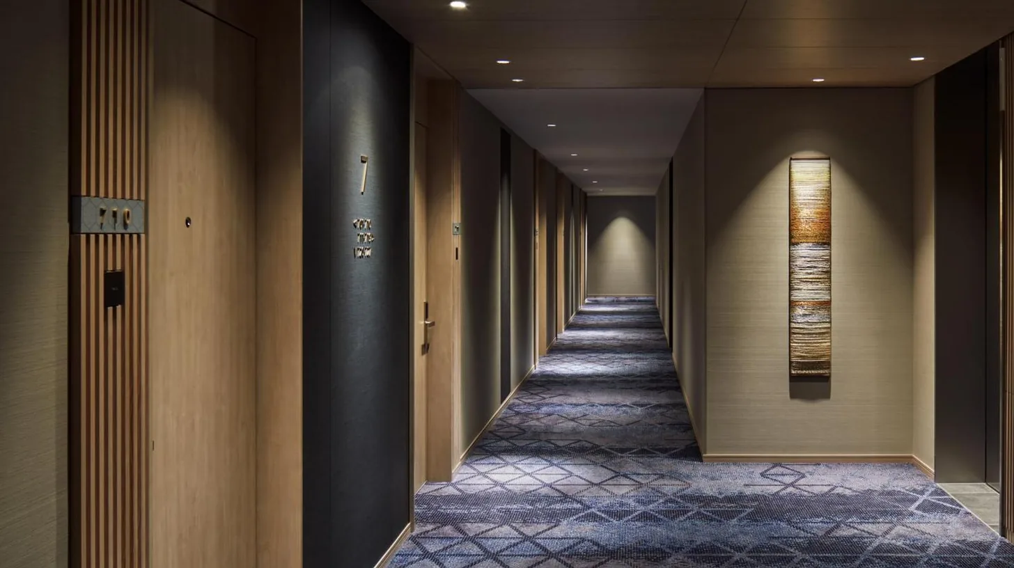 a corridor in a hotel with wooden walls and a long hallway at Hyatt House Kanazawa in Kanazawa