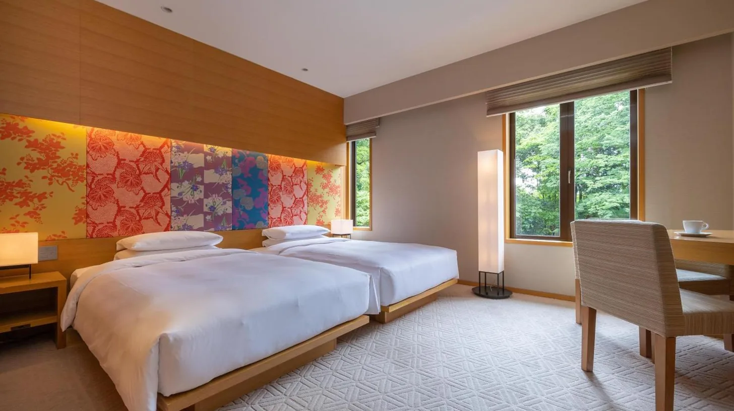a bedroom with a bed and a desk and two windows at Hyatt Regency Kyoto in Kyoto