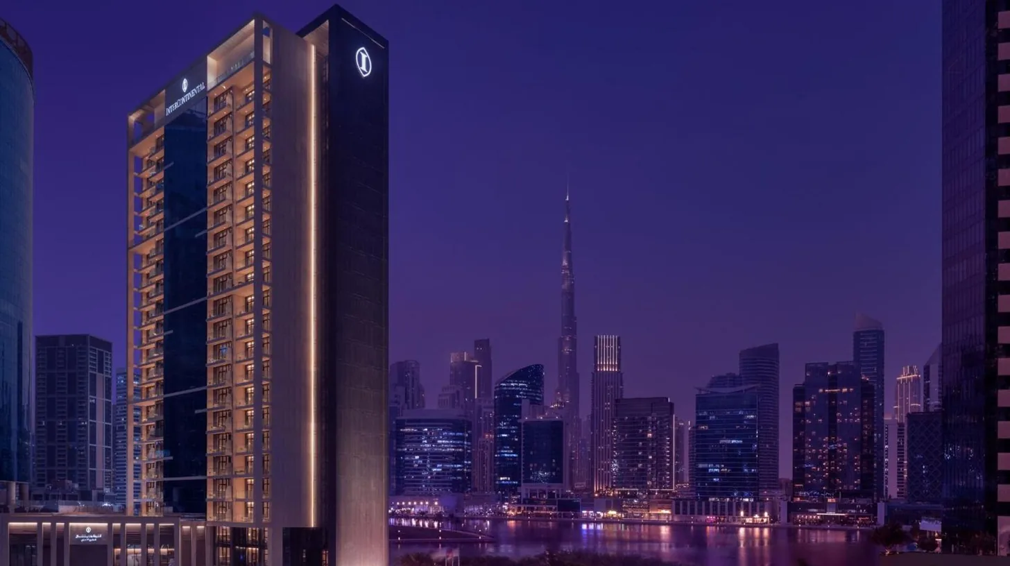 a tall building with a clock on it in front of a city at InterContinental Residences Dubai Business Bay by IHG in Dubai