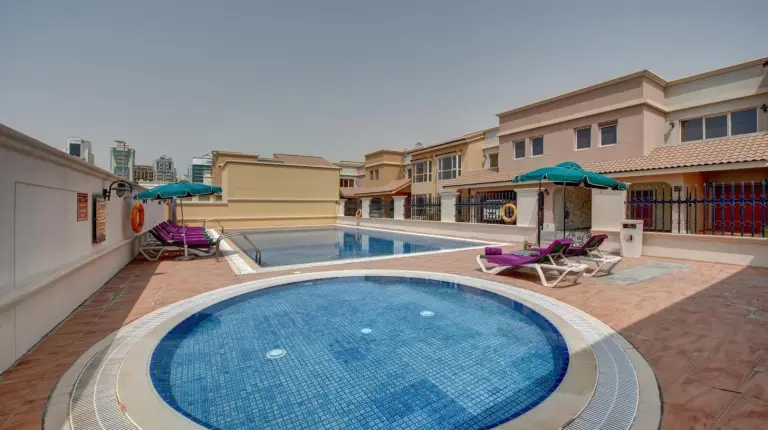 a swimming pool with chairs and umbrellas next to a building at J5 Villas Holiday Homes Barsha Gardens in Dubai