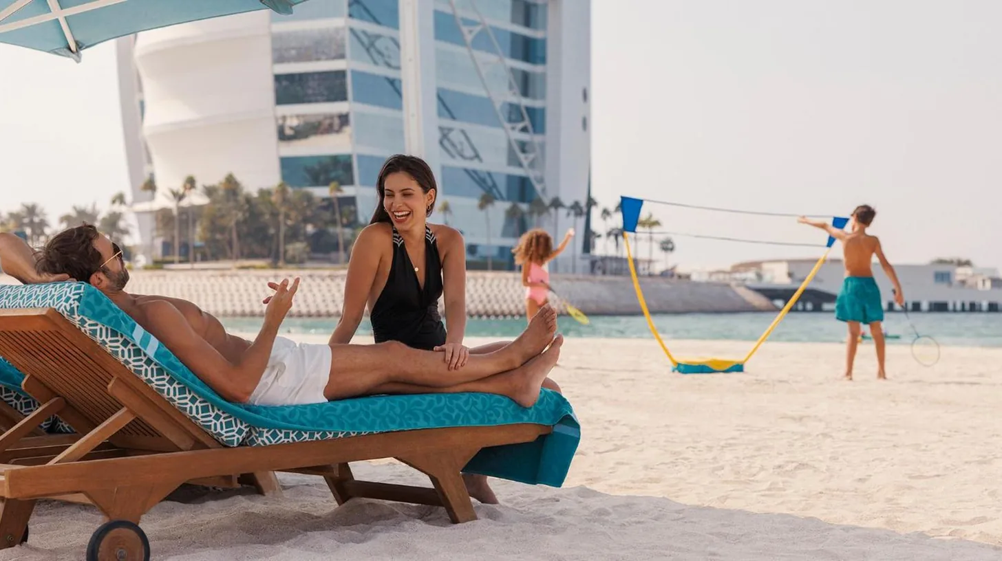 a man and a woman sitting in a chair on the beach at Jumeirah Beach Hotel Dubai in Dubai