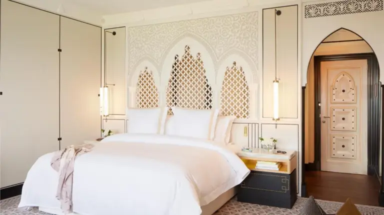 a bedroom with a large white bed and a mirror at Jumeirah Mina Al Salam Dubai in Dubai