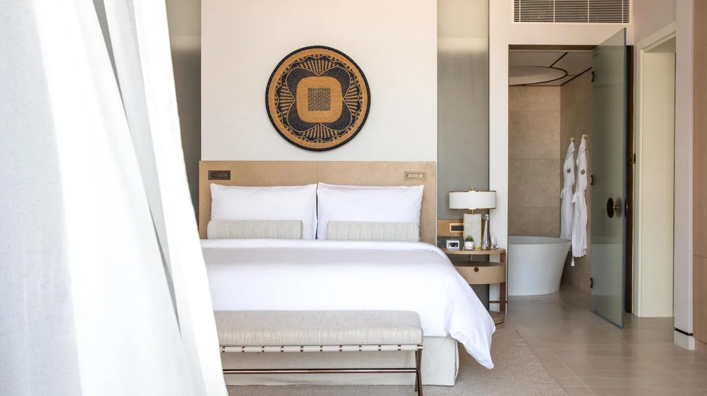 a bedroom with a white bed and a bath tub at Jumeirah Saadiyat Island Abu Dhabi in Abu Dhabi