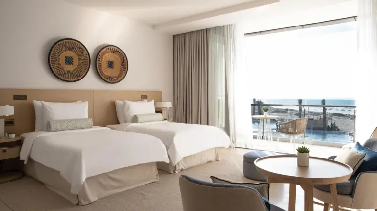 a hotel room with two beds and a table at Jumeirah Saadiyat Island Abu Dhabi in Abu Dhabi