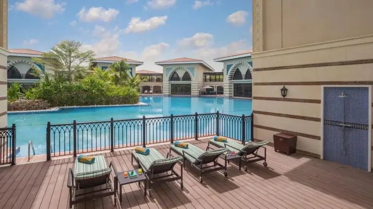 a balcony with a table and chairs and a swimming pool at Jumeirah Zabeel Saray Dubai in Dubai